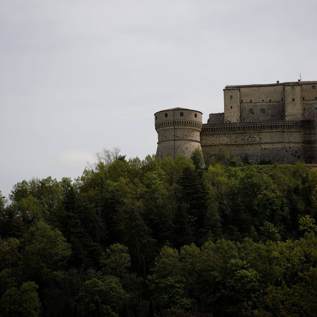 Château fort historique perché sur une hauteur entouré de végétation par temps nuageux