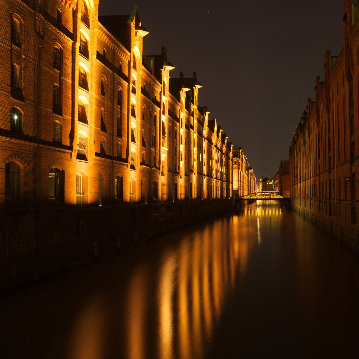 Canal historique illuminé la nuit, reflets de lumières chaudes sur l'eau